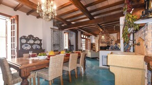 Zona pranzo con tavolo in legno, sedie in vimini e lampadario.