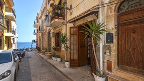 Una stretta via fiancheggiata da edifici, alcuni con balconi e piante in vaso.