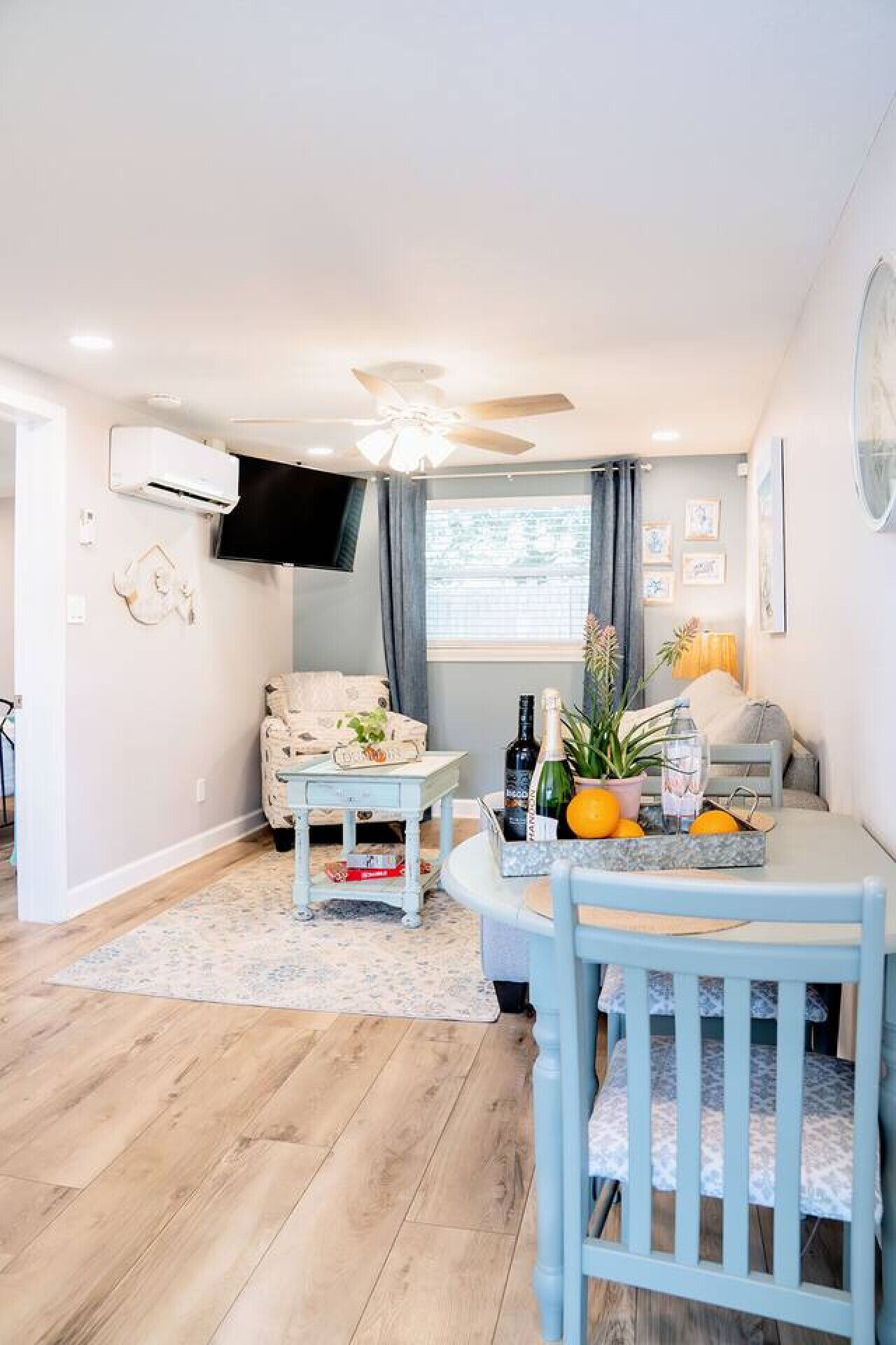 A cozy living room with a ceiling fan, a flat-screen TV, a sofa, a coffee table, and a dining table with chairs.