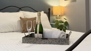 A neatly made bed with a tray holding a bottle of champagne, two glasses, and a folded towel.