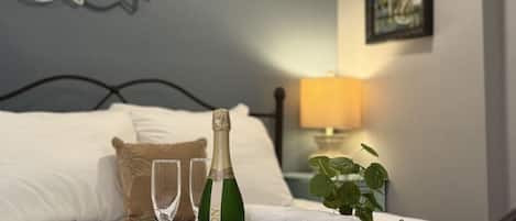A neatly made bed with a tray holding a bottle of champagne, two glasses, and a folded towel.