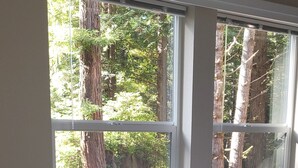 A bedroom with two windows, a bed, and a view of trees and a yard. - Fieldbrook Cottage in Redwood Forest (McKinleyville)