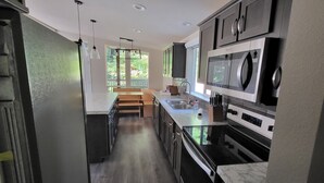 A modern kitchen with dark cabinets, a built-in microwave, and a sink. - Fieldbrook Cottage in Redwood Forest (McKinleyville)