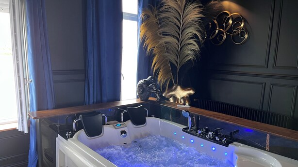 A modern bathroom with a jacuzzi, dark walls, and blue curtains. - La 104 private cocooning rooms with whirlpool bath (Saint-Omer)
