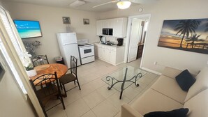 A compact living space with a dining area, kitchenette, and a sofa. - Beachside Cottage #3/ Fun In The Sun/Dogs Welcome (Redington Shores)