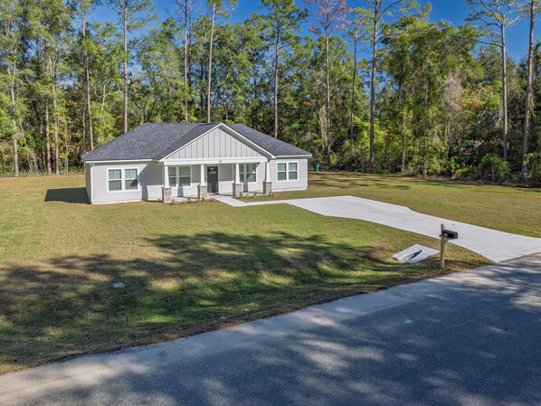 A single-story house with a front porch, a driveway, and a mailbox. - 4BR + near FSU/FAMU/Wakulla + firepit/BBQ on 1-acre (Crawfordville)
