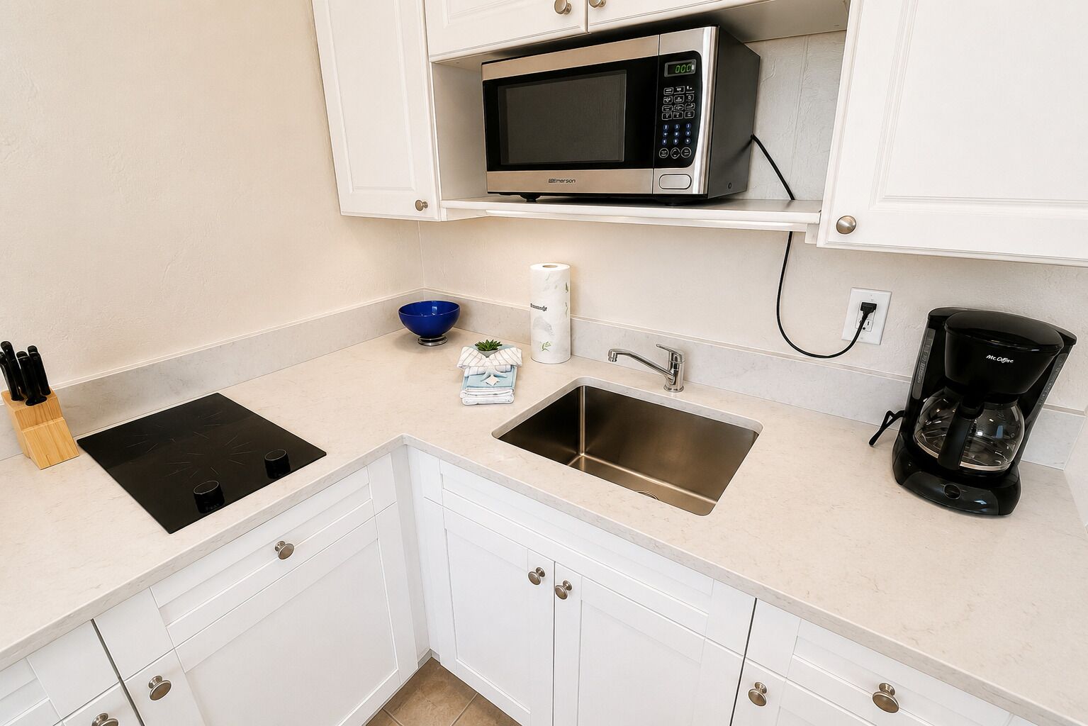 A kitchen with a built-in microwave, a sink, a coffee maker, and a stove.