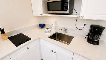 A kitchen with a built-in microwave, a sink, a coffee maker, and a stove.