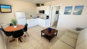 A compact living space with a kitchenette, a dining area with a table and chairs, a sofa, and a small coffee table. - Beachfront 1BR, Steps to Ocean, Dog Friendly. BOOK TODAY! (Redington Shores)