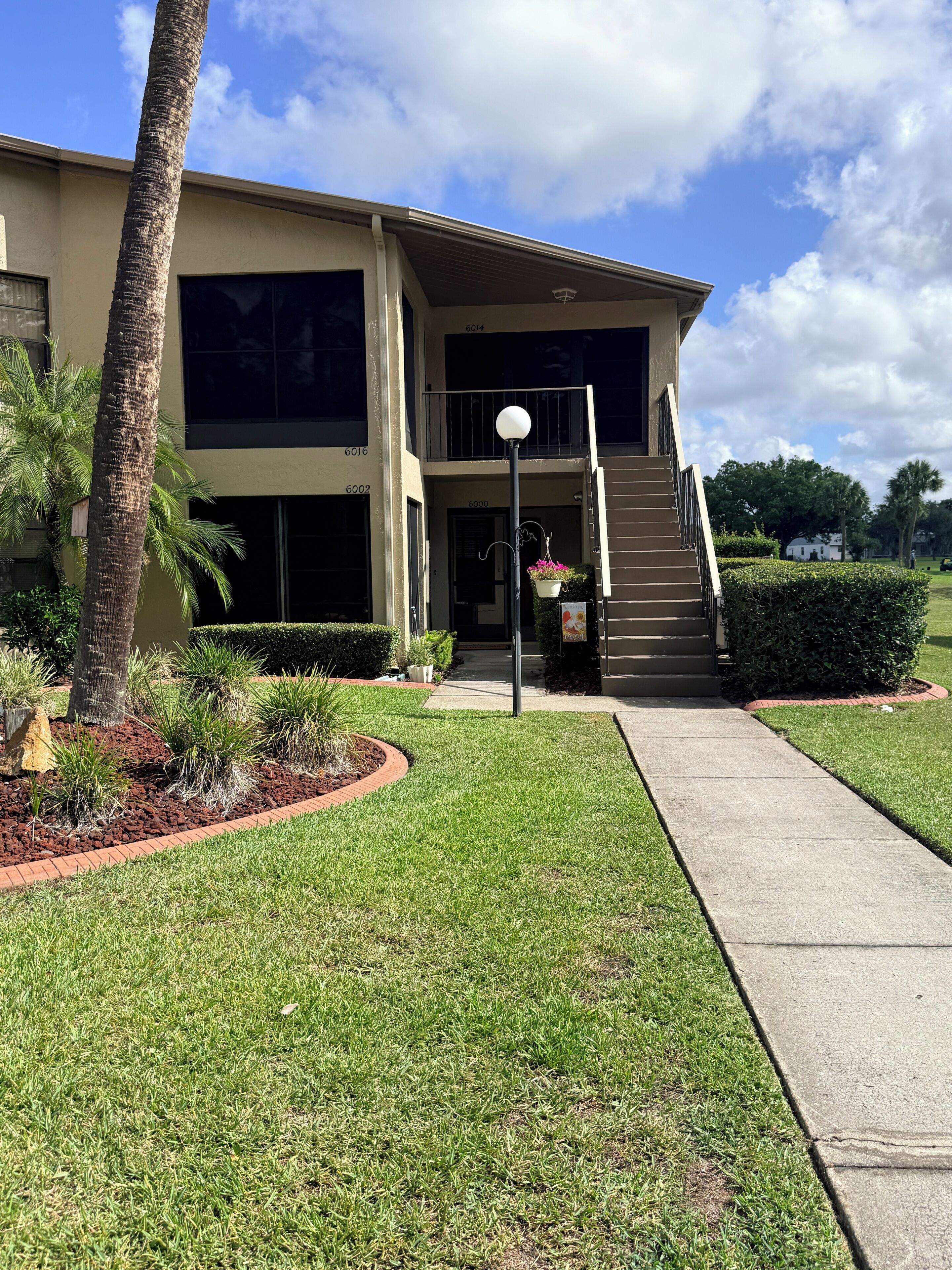A two-story building with a covered entrance, a staircase, and a well-maintained lawn.