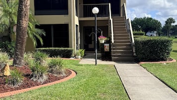 A two-story building with a covered entrance, a staircase, and a well-maintained lawn.