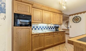 Una cocina con armarios de madera, salpicadero de azulejos y un reloj en la pared.