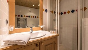 Ein Badezimmer mit Holztisch, Waschbecken, Spiegel und Duschbereich.