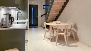 A modern kitchen with a built-in coffee machine, a dining area with a round table and wooden chairs, and a staircase with wooden steps. - Beautiful home in Bjorli (Bjorli)