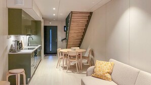 A modern kitchen with a built-in stove and a dining area with a round table and wooden chairs. - Beautiful home in Bjorli (Bjorli)