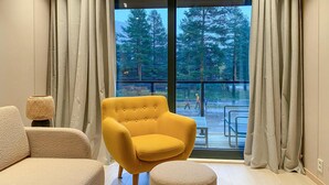 A modern living room with a yellow armchair, a round ottoman, and a lamp on a side table. - Beautiful home in Bjorli (Bjorli)