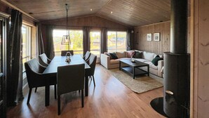 Ein gemütliches Wohnzimmer mit Essbereich, Kamin und großen Fenstern.
