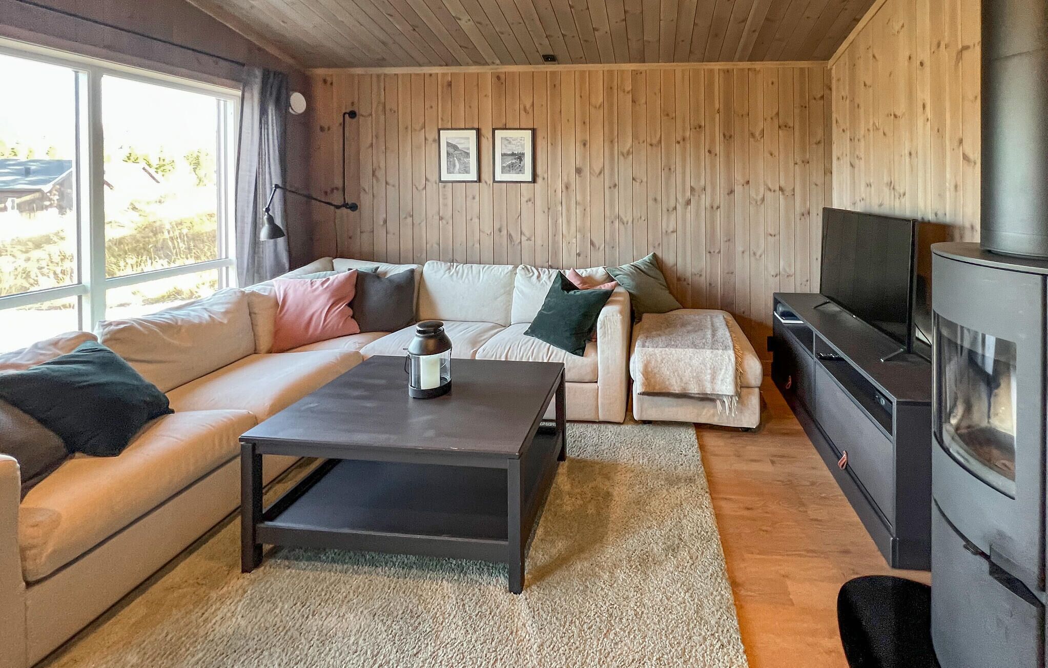 Una sala de estar acogedora con un sofá, una mesa de centro, una chimenea y cuadros en la pared.