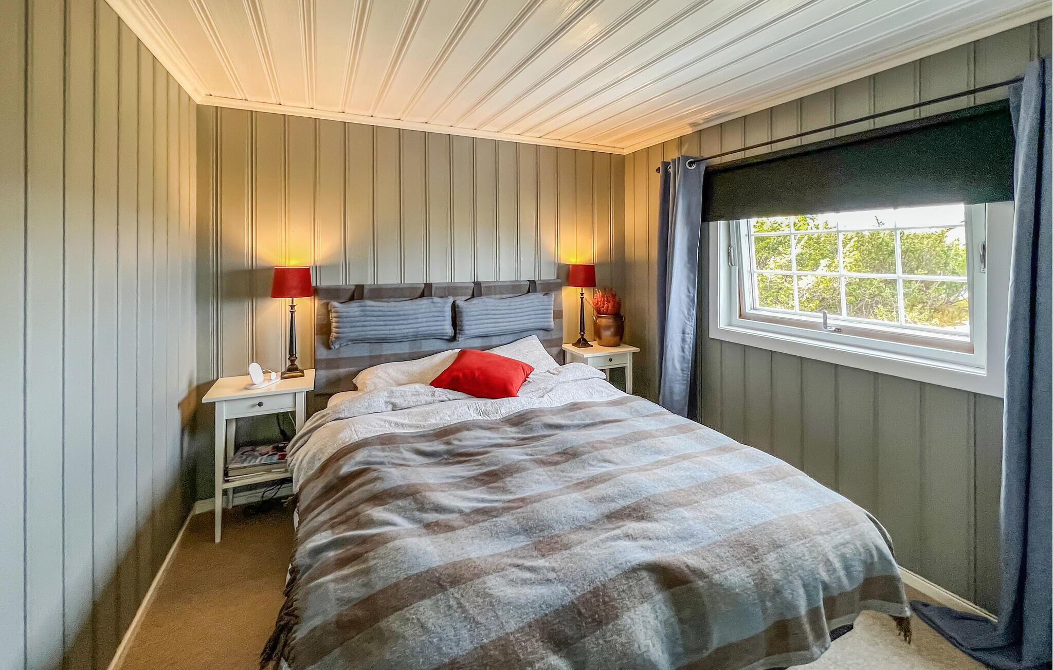 A bedroom with a bed, two bedside tables, a window, and a headboard.