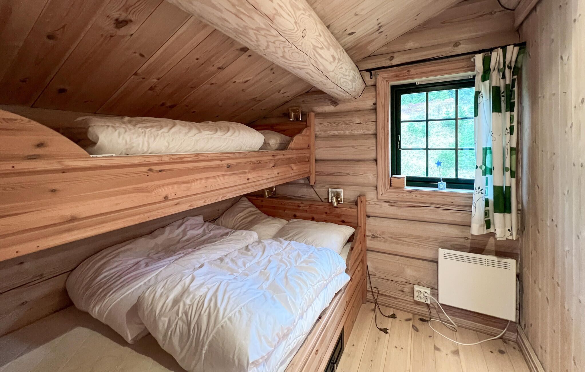 A cabin with two bunk beds, a window with curtains, and a wall-mounted heater.