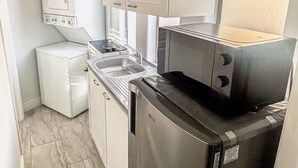 A compact kitchen with white cabinets, a built-in oven, a small refrigerator, and a sink. - Civic Centre, Compact Microapt layout & Sprt Entry (Gilbert)