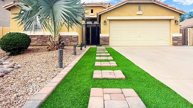 A residential driveway leading to a house with a garage, a palm tree, and a well-maintained lawn. - Civic Centre, Compact Microapt layout & Sprt Entry (Gilbert)