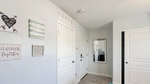 A hallway with white doors, a mirror, and motivational wall art. - Civic Centre, Compact Microapt layout & Sprt Entry (Gilbert)