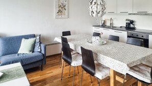 Une cuisine moderne avec des meubles blancs, une table à manger avec des chaises et un canapé bleu.