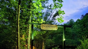 Un sentier en bois mène à une arche en bois sur laquelle est affiché un panneau indiquant : « Île privée du Bear Lake Lodge ».