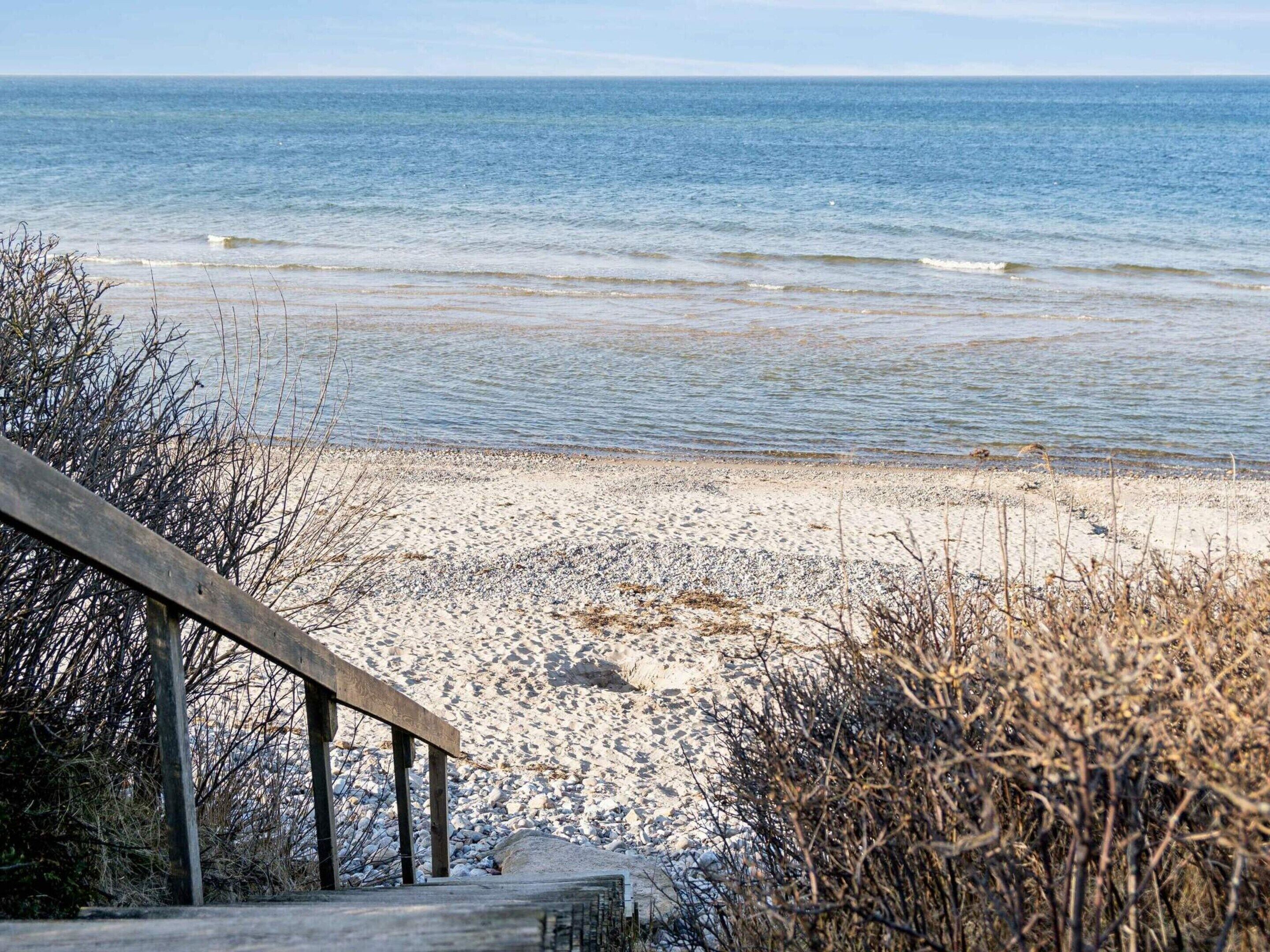 A beach with a wooden walkway leading to the shore.