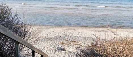 A beach with a wooden walkway leading to the shore.