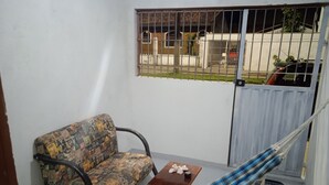 En lille balkon med en hængekøje, en mønstret sofa og et lille bord med en pynteting.