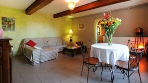 A cozy living room with a sofa, a dining table with chairs, a lamp, and a vase of flowers. - Mas d'en costeseque - BANYULS-DELS-ASPRES (BANYULS-DELS-ASPRES)