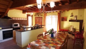 A cozy kitchen with a central island, a dining table with a quilt, and wooden beams on the ceiling. - Mas d'en costeseque - BANYULS-DELS-ASPRES (BANYULS-DELS-ASPRES)