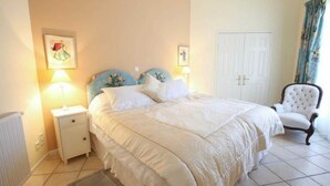 A bedroom with a large bed, a nightstand, a chair, and a door. - Boucheron - ST-LAURENT-DE-CERDANS (ST-LAURENT-DE-CERDANS)