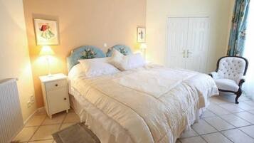 Une chambre à coucher avec un grand lit, une table de chevet, une chaise et une porte.