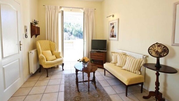 A living room with a sofa, armchair, TV, and a small table with a vase. - Boucheron - ST-LAURENT-DE-CERDANS (ST-LAURENT-DE-CERDANS)