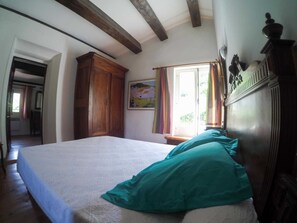 Quarto com cama, guarda-roupa de madeira e janela com cortinas.