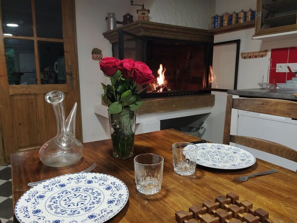 Una mesa de comedor con platos, vasos y un jarrón de rosas.