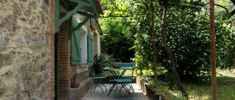 A stone building with a small outdoor seating area, including a table and chairs, and a potted plant.