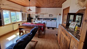 L’intérieur chaleureux d’un chalet comprend un coin repas, une cuisine et une grande fenêtre donnant sur la forêt.
