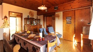 Un coin repas en bois avec une table dressée pour quatre personnes, un plafond en bois et une porte en bois ornée d’une affiche.