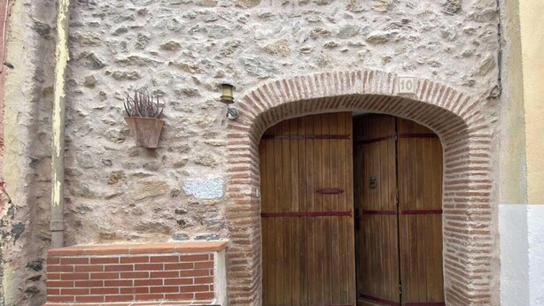 A stone building with a wooden door and a brick bench.