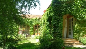 Un jardin luxuriant avec une maison, un poteau d’incendie et des marches menant à une porte.