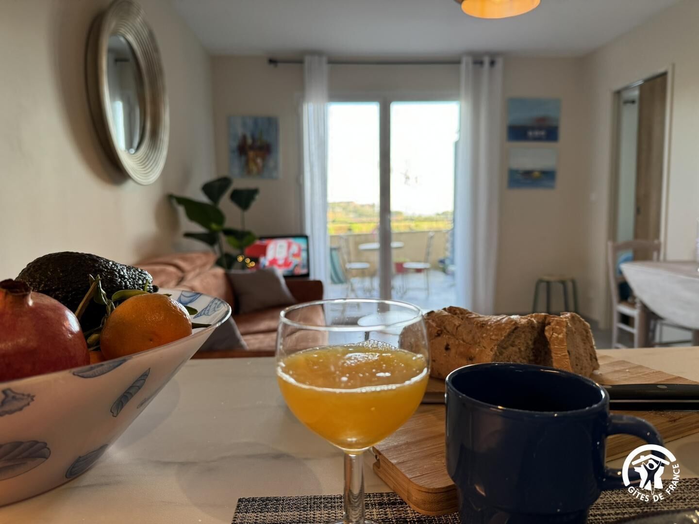 Ein Essbereich mit einem für das Frühstück gedeckten Tisch, mit Früchten, Brot und einem Glas Orangensaft.