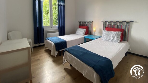 A hotel room with two beds, a desk, a chair, and a window with curtains. - Le coscollet 2 - ILLE-SUR-TET (ILLE-SUR-TET)