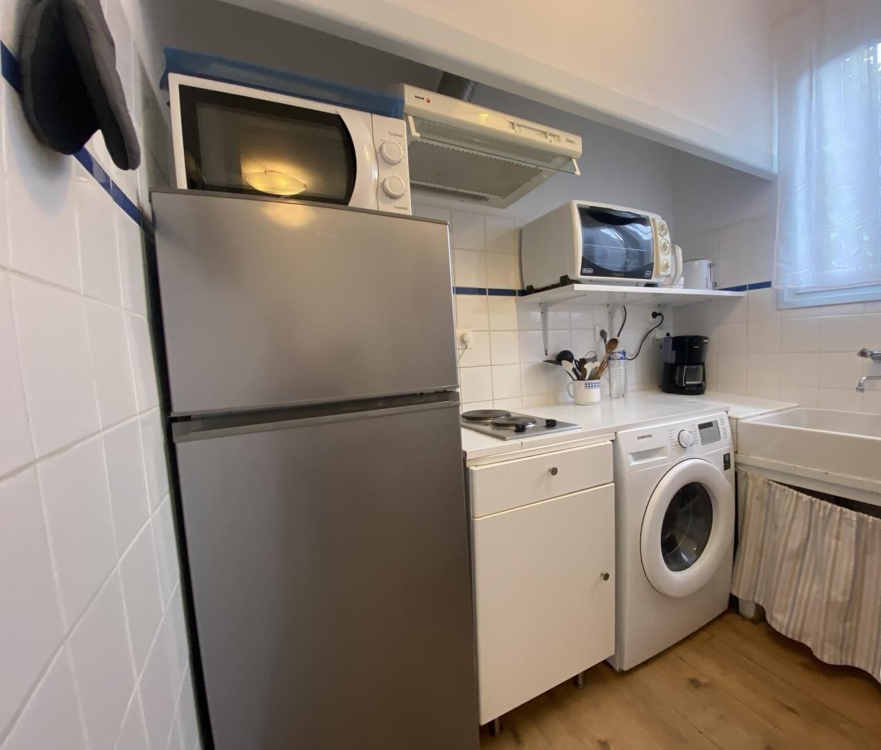 Cocina compacta equipada con refrigerador, microondas, estufa y lavadora.