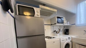 A compact kitchen with a refrigerator, microwave, stove, and washing machine. - Le coscollet 2 - ILLE-SUR-TET (ILLE-SUR-TET)