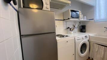Cocina compacta equipada con refrigerador, microondas, estufa y lavadora.