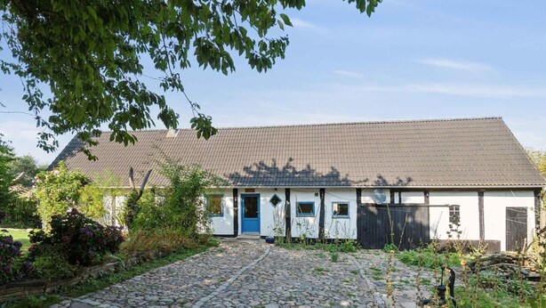 Een traditioneel huis met een grindpad, een blauwe deur en een pannendak.
